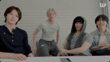a group of young men are sitting around a table and one of them is wearing a beanie that says owe on it