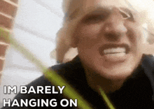 a close up of a person 's face with the words " i 'm barely hanging on " above it