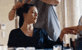 a woman is getting her hair done by a hairdresser