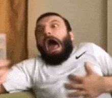a man with a beard is making a funny face while wearing a nike shirt .