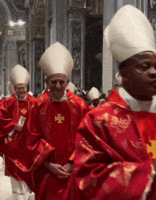 a group of priests are walking in a church and one of them has a cross on his vest