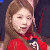 a close up of a woman wearing a red shirt and a microphone in her mouth .