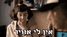 a woman with a bun on her head is smiling with the words " אין לי אויר " written below her
