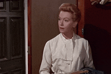 a woman standing in front of a door holding a hanger