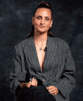 a woman in a gray striped jacket is holding a black box