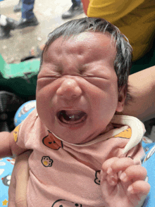 a baby is crying and wearing a pink shirt with hello kitty on it