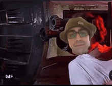 a man wearing glasses and a hat is standing in front of a robot .