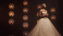a woman in a wedding dress stands in front of a wall of lit candles