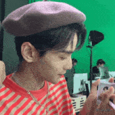 a young man wearing a purple beret and a red and white striped shirt