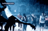 a group of people are standing in a dark room with a person flying in the air .