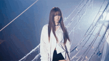 a woman with long hair wearing a white shirt and black skirt stands in front of ropes