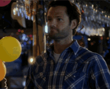 a man in a blue plaid shirt is standing in front of a yellow balloon