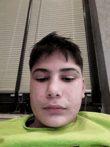 a close up of a person 's face with a green shirt on