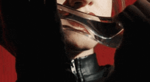 a woman is holding a glass in front of her face