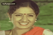 a close up of a woman 's face with a red bindi on her forehead and smiling .