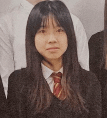 a young girl in a school uniform and tie is posing for a picture with her friends .