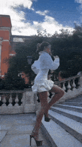 a woman in a white dress is standing on a set of steps