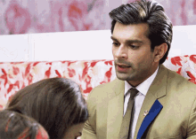 a man in a suit and tie is talking to a woman on a couch