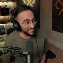 a man wearing headphones and glasses is sitting in front of a microphone in a room .