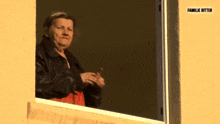 an older woman looks out of a window with the words familie ritter on the corner