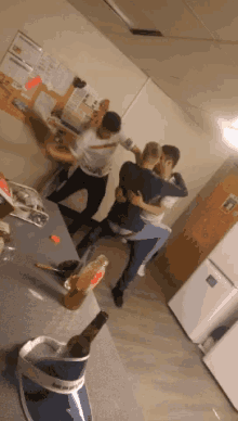 a group of people are dancing in a kitchen with a bottle of coca cola on the counter