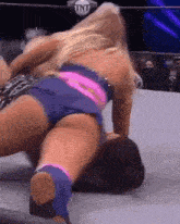 a woman in a pink and blue outfit is wrestling another woman in a wrestling ring .