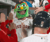 a red sox baseball player wearing a green sesame street mascot hat
