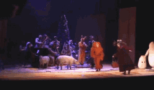 a group of people on a stage with a sheep in the foreground