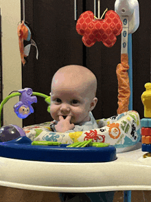 a baby is sitting in a blue and white jumperoo with toys hanging from it