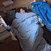 a person sleeping in a sleeping bag with a blue blanket