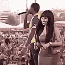 a man is singing into a microphone while standing next to a woman .