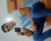 a man wearing sunglasses is sitting on a couch holding a cup