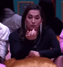 a woman is sitting at a table with her hands in her pockets and making a face .