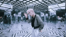 a man with pink hair is standing in a room with a striped floor and a mirrored ceiling .