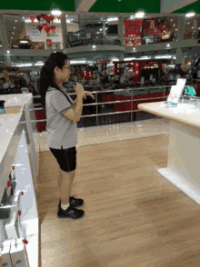 a woman in a grey shirt and black shorts is standing on a wooden floor
