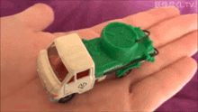a person is holding a toy truck in their hand .