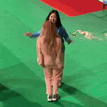 two women are hugging each other on a green mat