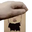 a hand is holding a picture of a man 's face on a piece of paper .