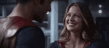 a man and a woman are smiling and looking at each other .