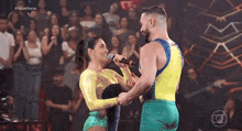 a woman singing into a microphone next to a man in a yellow and blue outfit