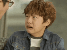 a young boy wearing a denim jacket is making a face