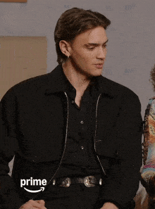 a man in a black jacket is sitting next to a woman in a colorful dress and the word prime is on the bottom of the screen