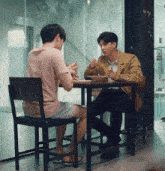 two men are sitting at a table with a sign that says no smoking