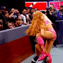 two women are wrestling in front of a crowd and one is wearing pink boots with the letter uf on them