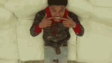 a young man is laying on a couch with his mouth open and making a funny face .