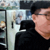 a man wearing glasses is sitting in a chair in front of a fridge