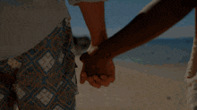 a man and woman holding hands on a beach