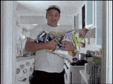 a man is holding a bag of chips and a bunch of cans .