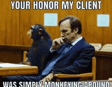 a man in a suit is sitting in a courtroom with a chimpanzee on his lap .