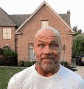 a man with a beard is making a funny face in front of a brick house .